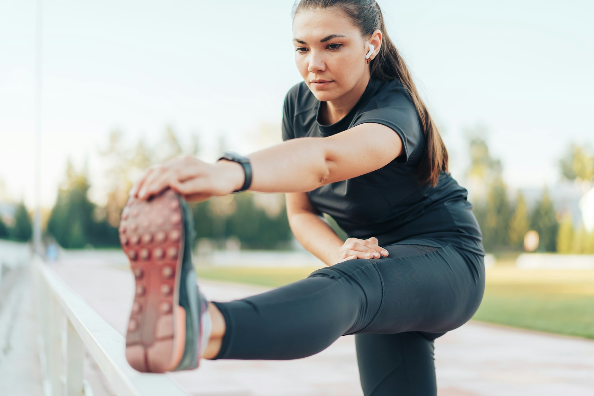 Girl in sportswear doing leg stretching in sports stadium